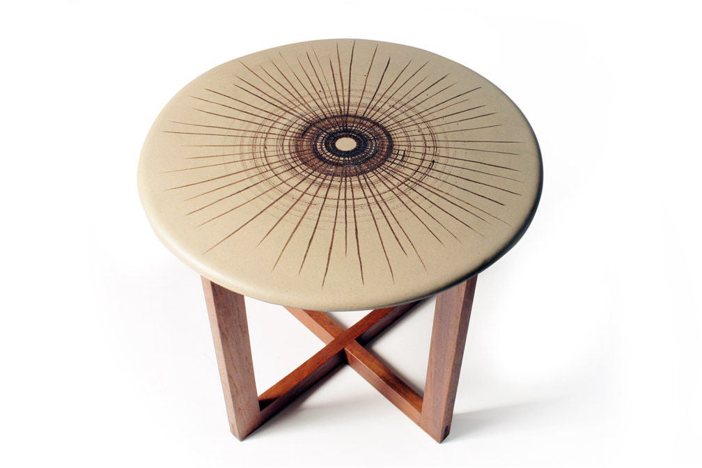 A mod occasional table comprising a circular ceramic top with concentric circle motif supported by a walnut cruciform base. By Design Technics. American, circa 1950.