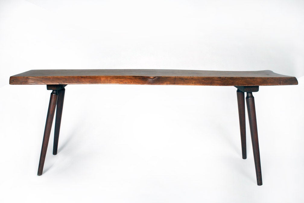 A long cocktail table with a free-edge single slab of walnut and supported by four turned wood legs. With partial artists label to the underside [Roy Sheldon Marlboro, Vermont Fabulous Tables Sliced on the Bias from Forest Trees]'. U.S.A., circa