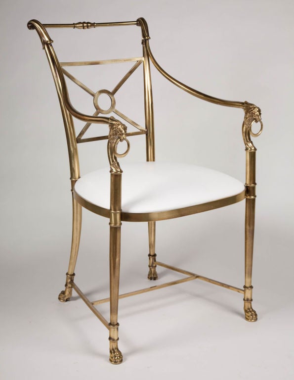 A pair of Regency armchairs in antique brass comprising a leather upholstered seat, X-form back rest, lion’s head arm rests, H-stretchers, and paw feet all in solid brass. By Weiman/Warren Lloyd. Italy, circa 1970.