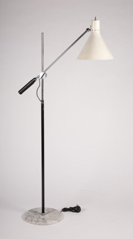 A single boom arm floor lamp with a leather wrapped grip, off-white enameled metal shade, and circular Carrara marble base. Stamped to the base “Made In Italy”. By Arredoluce. Italian, circa 1960. length of arm: 29”; diameter of cone shade: 10 3/4
