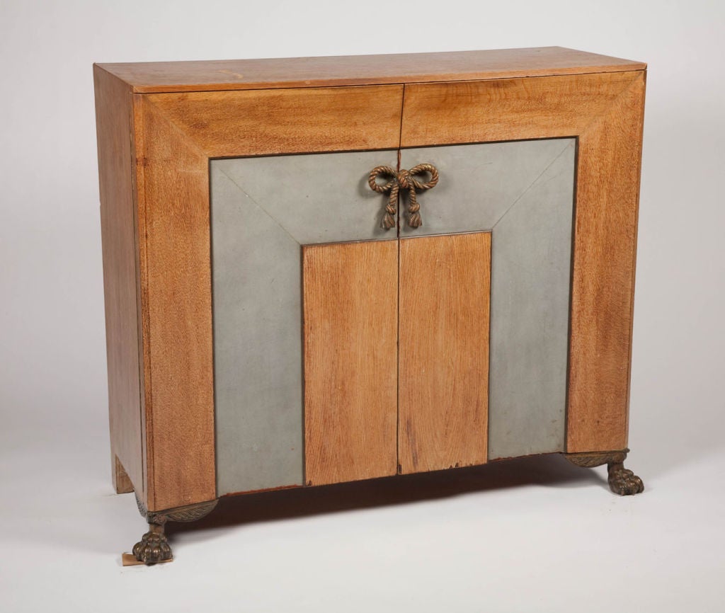 An exquisite cabinet or sideboard in solid oak with inset leather and interior chamfer cut to the outer edge of the two large doors. Bronze rope handle in the form of a bow and two bronze lion claw feet to the front and two wooden bracket feet to