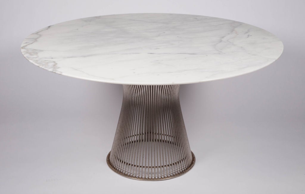 An iconic dining table comprising an elegant circular Carrera marble top supported by a polished nickel wire frame base.  By Warren Platner for Knoll. American, circa 1960.