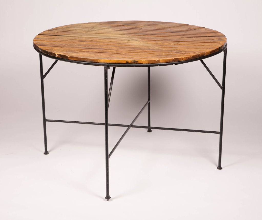 A wonderful set comprising four chairs with paper-cord roped back rests and molded wood slat seats, and a dining table with wood slat top; each rests on a wrought iron base with four legs, and the table has an X-stretcher. By Arthur Umanoff for