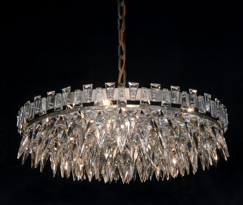 An exquisite chandelier in a crown of thorns motif containing triangular shaped crystals ordered within a brushed steel frame with six concentric bands. By Lobmeyr. Austrian, 1960.