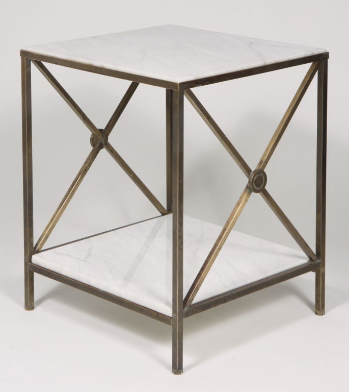 An austere pair of end tables in the Directoire style, comprising a Carrara marble top and lower shelf resting within a brass X-framed base.  By Maison Jansen. Italian, circa 1960.