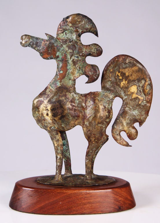 A diminutive bronze sculpture of a majestic horse with a flowing mane and tail rests on an oval wooden base. Signed and dated [Bill Lett ‘69]. U.S.A., circa 1969.