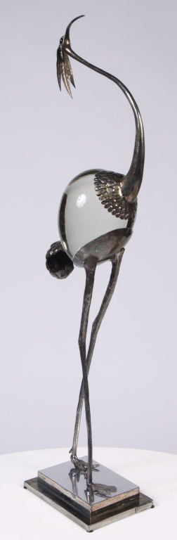 A graceful sculpture of a slender crane, its body is a large smooth crystal and its head, neck and legs are in silver plate with details in low relief throughout; the whole rests on a silver plate stand. Marked [Franco Lafini Made in Italy]. Circa