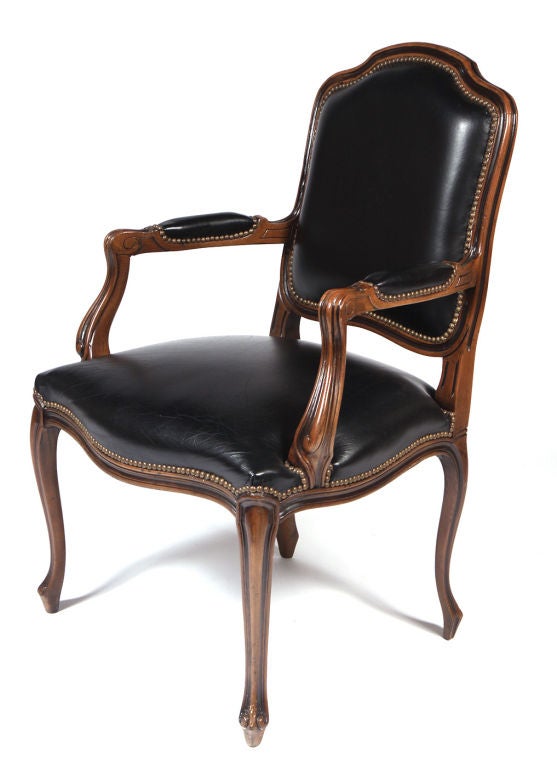 A fine pair of fauteuils with carved walnut frames upholstered in black faux leather with brass nail head detailing throughout. By Chateau d’Ax Italian, circa 1970.