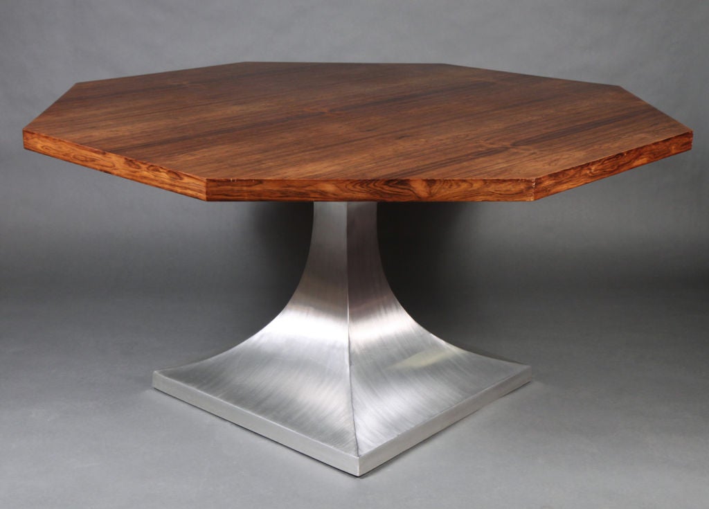 A mod dining table with an octagonal walnut top resting on a square brushed aluminum flared column pedestal base.  After Harvey Probber. American, circa 1960.