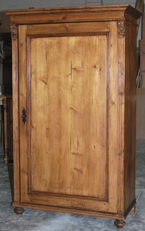 Rustic Bohemian wardrobe with carved capitals on fluted pilasters and bun feet. The interior has original pegs for hanging clothes. A hanging rod was added later. Please note that this piece is dove-tailed top and bottom. Lock and key work. We can