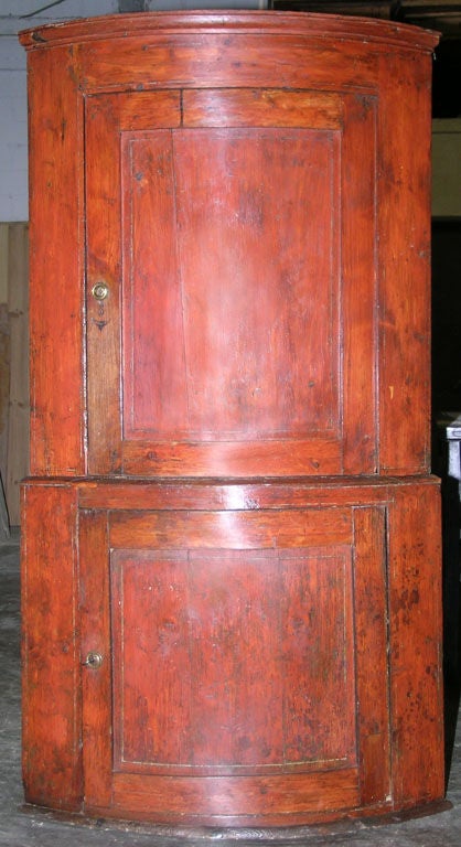 Corner cupboard in two parts with rounded front and working locks. The original rusty red color was popular during the late 1700s, this cupboard shows a lot of character and charm.

  