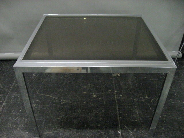 Polished steel Table extends from each side to double in size by sliding the top out to reveal a duplicate that also slides out and lock in at the same height. The table is very easy to operate and is very sturdy. Both tops are smoked, tempered, and
