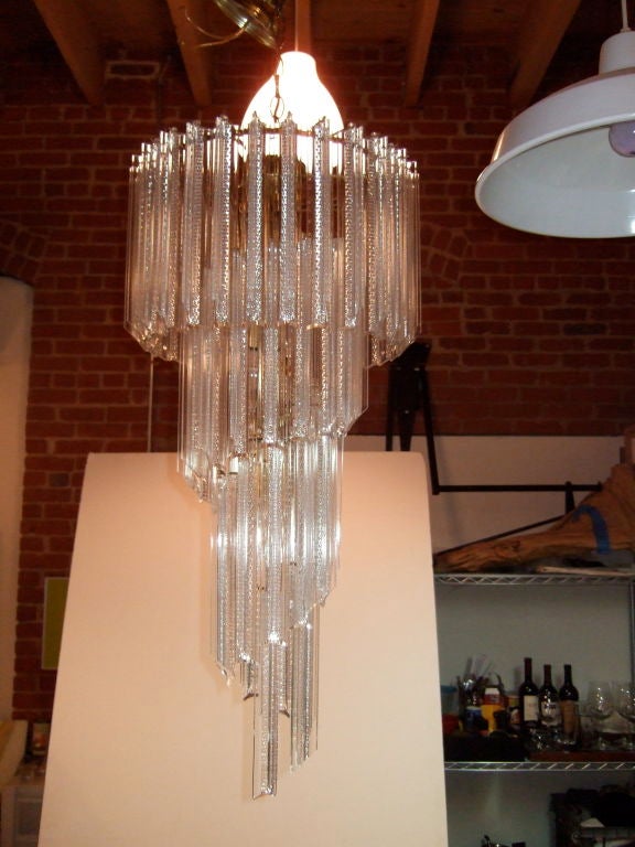 Spectacular large spiral Lucite prism chandelier. This chandelier has beautiful bevel shaped Lucite prisms that each have detailed cut patterns on them. The form is a brass-plated metal which twists with arms to hang the prisms on. Five small tipped