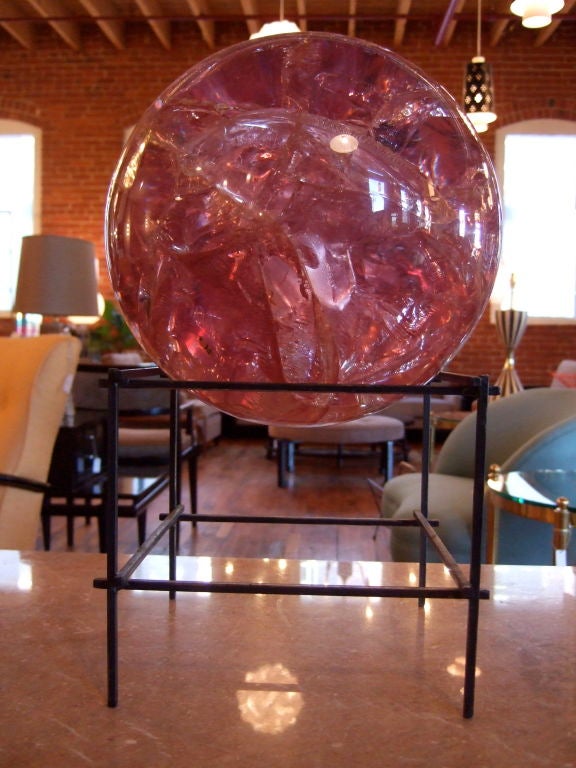 Pink fractured lucite ball perched on a black metal stand.  The pink ball is is translucent with cracks all over the ball.  Black metal stand is welded at each corner with slight overlap.<br />
<br />
Please visit our gallery in Stamford,