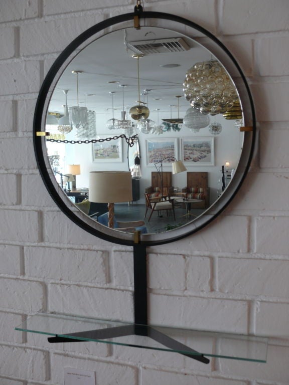 Great Italian wall hanging mirror made of black iron, floating mirror with brass hardware and glass shelf. Delicate and lovely piece.
