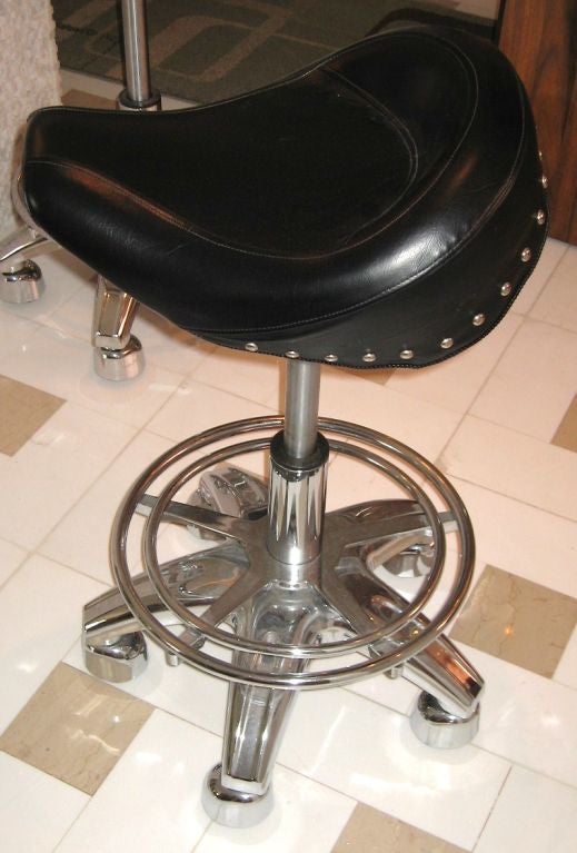 Contemporary set of four heavy duty chrome over steel barstools with thick black matte vinyl seating. Designed to resemble motorcycle seats with chrome studding. Lightly used in a model home setting, ready to use and enjoy.