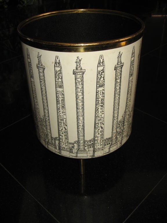 Fantastic find, this late 50's wastepaper basket by Fornasetti of Milan is rendered in glazed enamel over copper, and is supported by tapered brass bullet form feet. Off-white and black decoration depicting alternating images of the Colonne