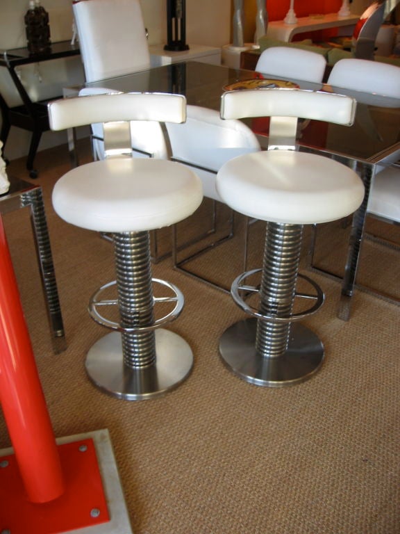 Pair of bar stools with round layered disk pedestal stands. Chrome over steel  rounded foot rest and brushed aluminum round base. All of that covering an iron inner frame giving these stools ultimate stability. A T-bar back rest also chrome over