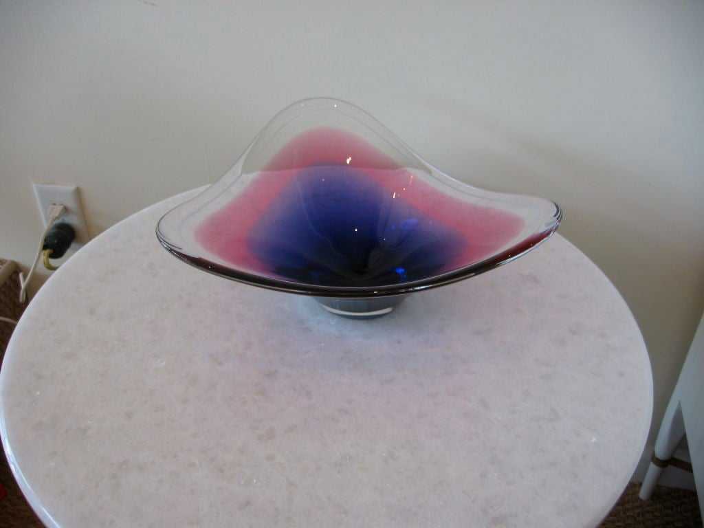 Wonderful biomorphic shaped glass bowl with deep purple to black at mid center moving into blue purple then moving into purple. A white infused line frames the entire perimeter. The shades of color are warm and inviting. Signed but illegible and