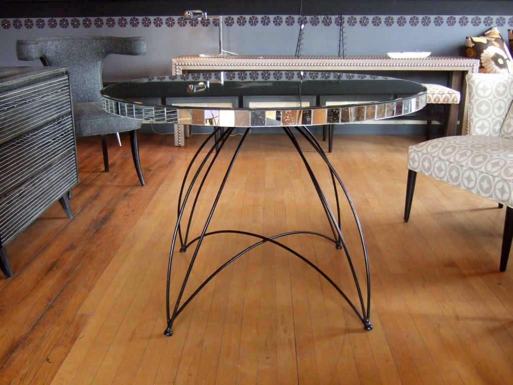 Simple beauty lies in its open presentation of materials, construction and design.  Iron table with mercury mirror top with mirrored trim.