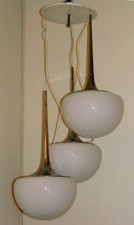 Sleek Italian 70's chandelier by the well known company Reggiani.  Three chromed and glass pendants hang from an off white canopy. The length of the three pendants can be adjusted within a certain range.