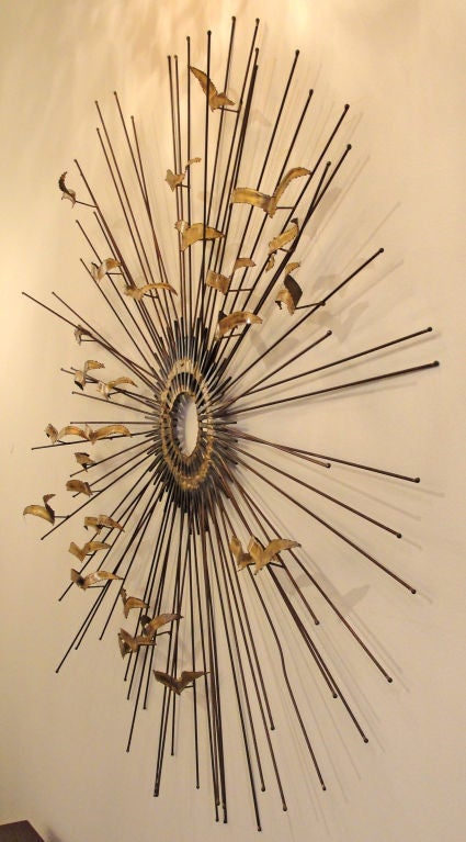 Whimsical sculpture showing a flying birds against a sunburst.  Birds are in brass. Sun rays are flat iron nails and copper rods welded with brass. A mirror can be applied on request in the central disc. Unsigned
