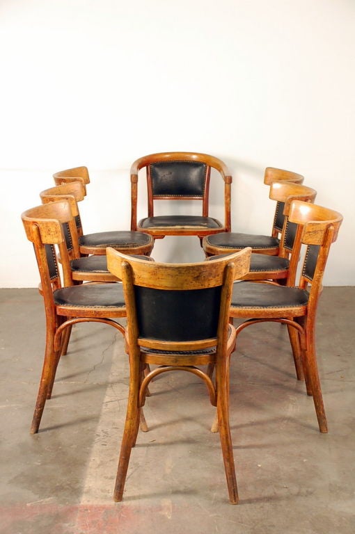Set of 7 + 1 French bistro early 20th century dining chairs. One host armchair and 7 side chairs. Very comfortable curved backs. Standard 18 in. seat height.