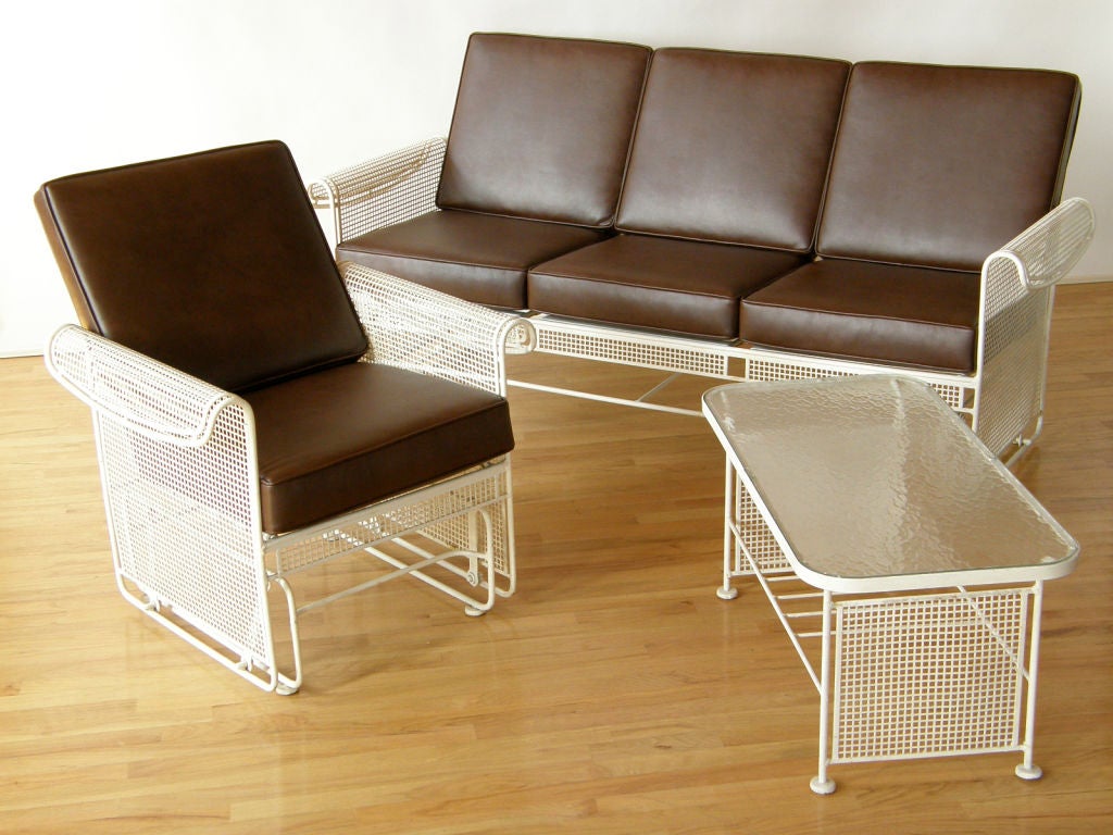 Very unusual glider sofa and chair with matching table, possibly made by Woodard. Perforated metal frames, reminiscent of metalwork from the Bauhaus, give the pieces a solid yet transparent appearance. <br />
A good 'machine age' style design