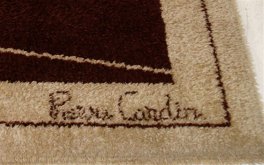 Signature area rug by Pierre Cardin. Design is created by four rotating, interlocking P's, one of Mr. Cardin's most iconic uses of his initials. Dark brown and tan wool, in excellent condition. Signed in corner of rug.