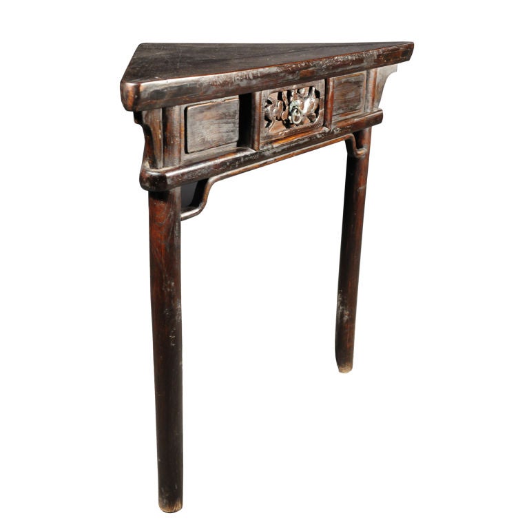 A 19th century Chinese triangular form corner table with three legs, floral carved drawers and a rich patina.