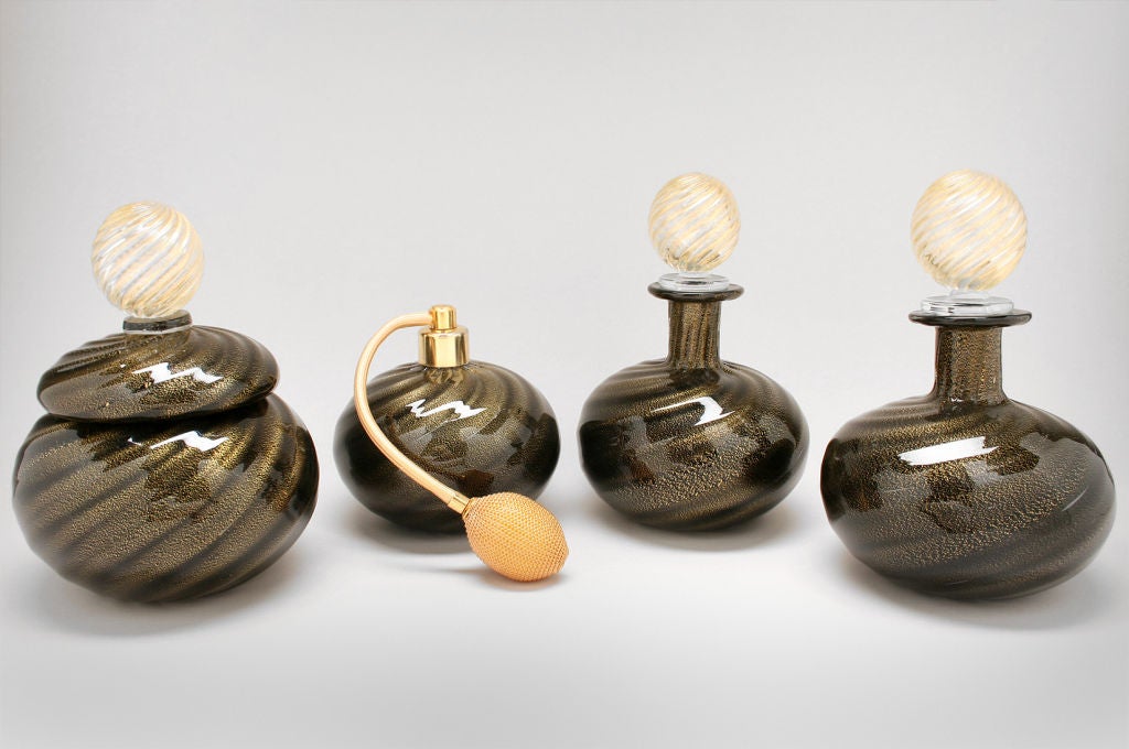 This is a handsome dresser set which includes a covered powder jar, and atomizer and two perfumes. The Italian glass pieces are black glass swirled with gold.<br />
<br />
The pieces meaure from LT to RT:<br />
The jar measures 6 1/2