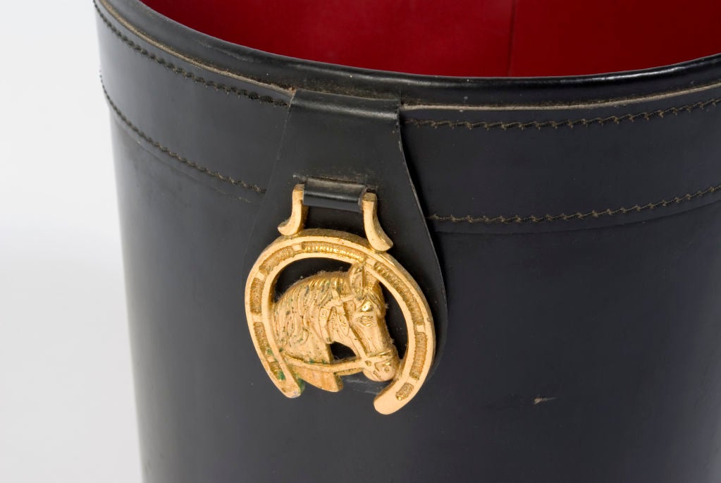 Very cool black leather trash can with red interior and brass horse head inside horseshoe.
