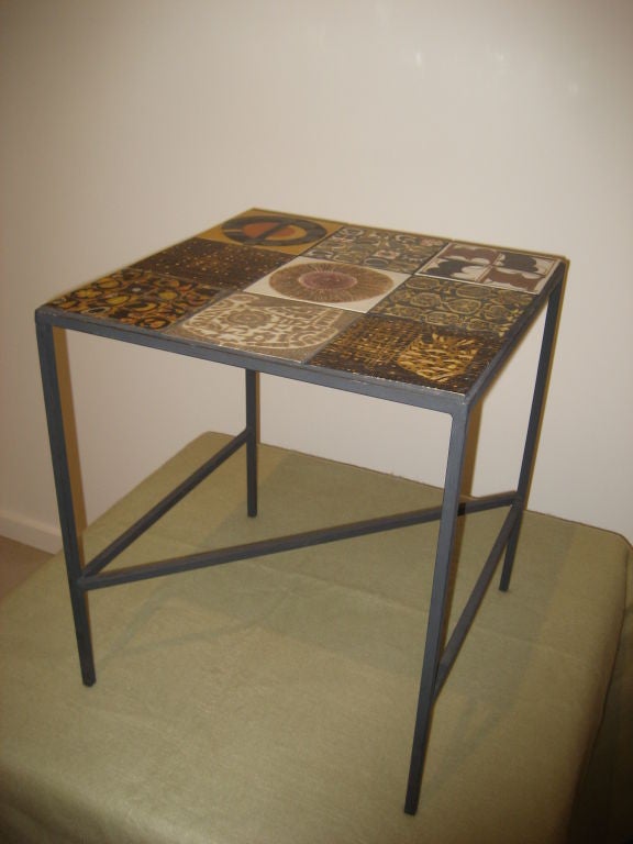 Mid Century Modern multi- tile top table with iron framework and legs. The tiles are each unique patterns including stylized birds fish and circular motifs. The attribution is Scandinavian due to the color and matte finish of the tiles.