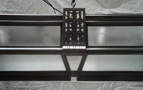 An American Art Deco horizontal flush mounted ceiling light with textured glass inserts and stylized floral and geometric open fret sections.