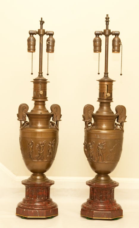 A pair of signed Barbedienne French Empire style bronze urn-shaped table lamps detailed with low relief Classical frieze supported by fluted rouge-marbre bases. Converted from oil to electric. Signed by reknowned foundry.