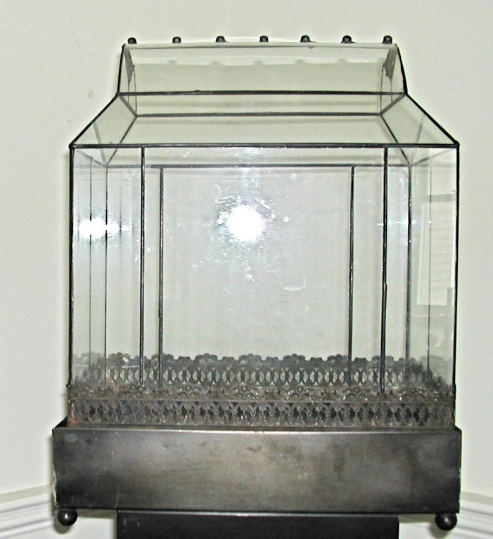 This beautiful vintage table top terrarium has many fine details. Ball feet on the base, filigree work on the bottom of the glass structure as well as on the roof line venting area. There is a row of decorative ball shaped roof adornments. Truly a