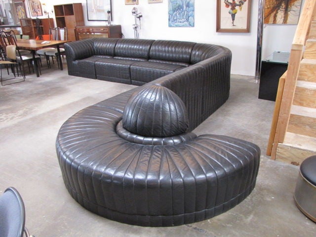 The black leather is stitched in a ribbed vertical line pattern and the couch’s shape is up to you, as each of the seven pieces can be placed in any outline desired. <br />
It is very difficult to give the exact overall measurements. Please call us