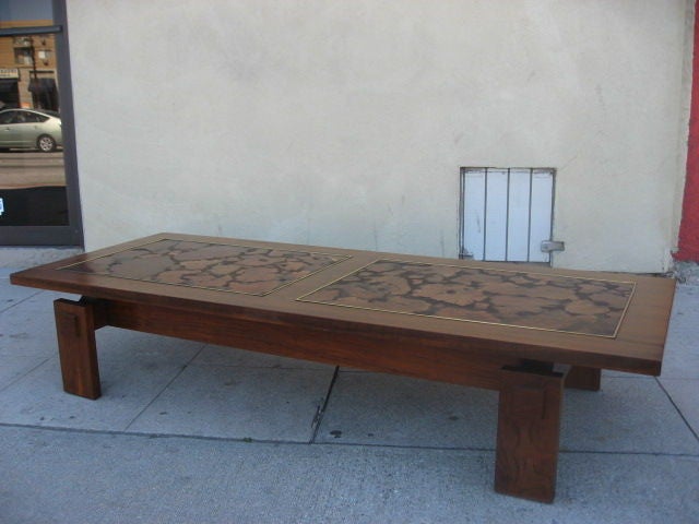 Walnut table with inlaid burl wood pattern and brass frame detail.