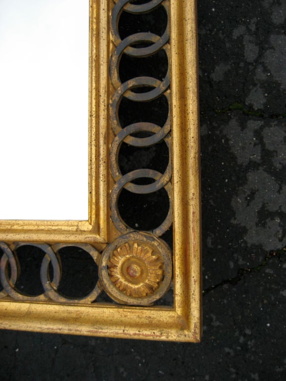 Beautiful carving distinguishes this gilt wood mirror made in Italy for LaBarge.  Center frame is bracketed with pierced interlocking circles.  Round flower form appliques at the corners.