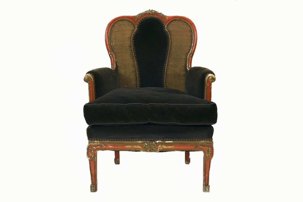having a floral finial above a triple arched crestrail and a middle upholstered backrest flanked by two caned panels, with outwardly scrolling half-upholstered arms, the down cushion above transitional legs, painted throughout in faded reds with
