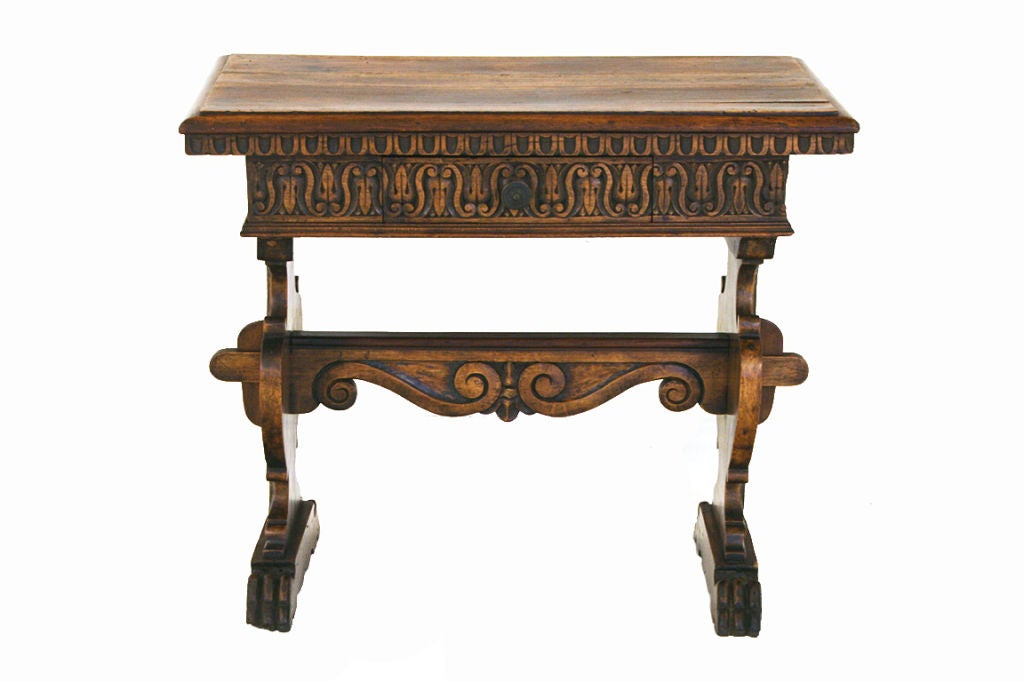 having a molded edge rectangular top with an overhanging dentile molded edge above a carved drawer and supported by two urn-shaped carved legs with traces of gilding, the legs joined by a carved and pegged stretcher, resting on animal paw bracket