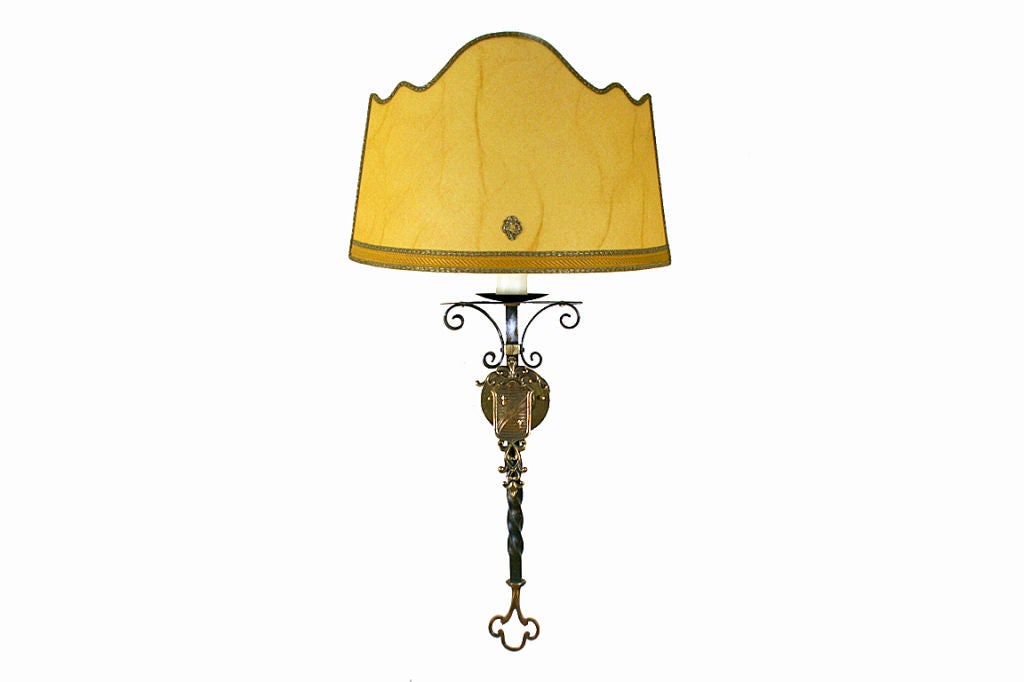 having later custom lace trimmed shades, the sconces with c-scrolls at the tops and having decorative shields, the lower twisted iron portion ending in a decorative brass terminal