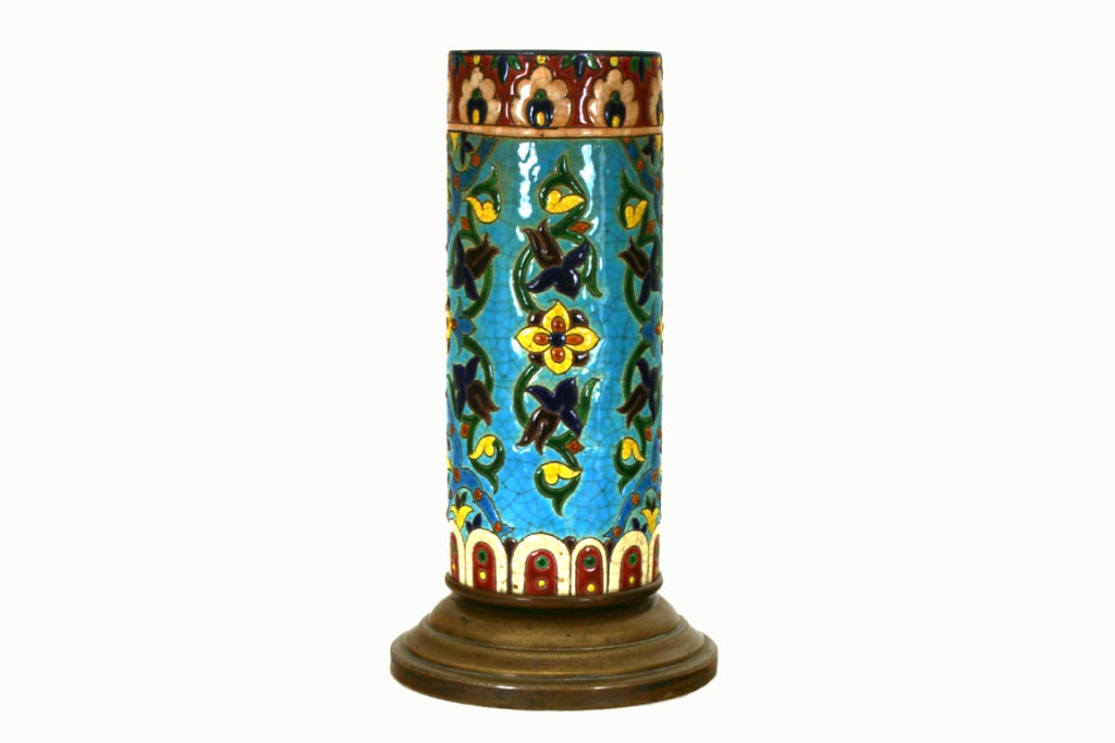 Zylindrische Form mit lebhafter Bemalung in Türkis, Gelb und Kastanienbraun mit blauen und grünen Akzenten, die Blumen und Weinformen darstellen.

 