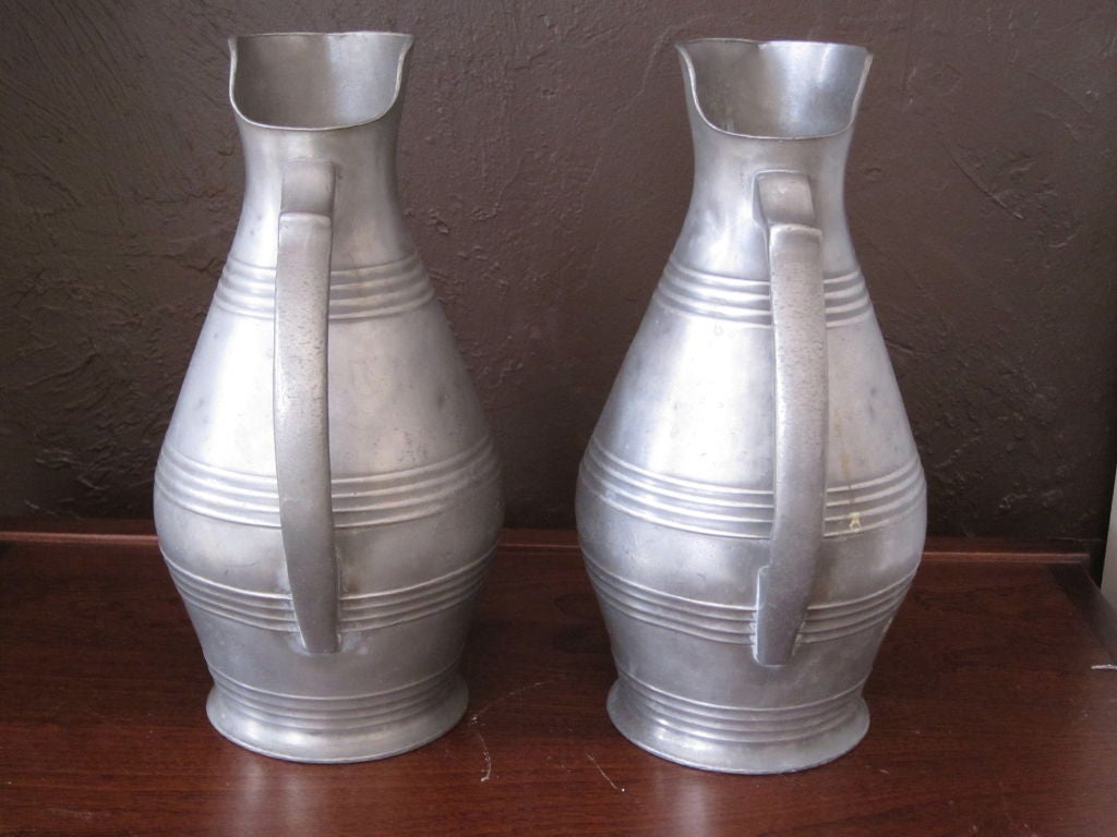 This is a very unusual pair of Pewter pitchers.  The long line is made not only from the tall height of the pitchers, but from the slightly elongated spout as well as the gently tapering handle.  The pitchers have four sets of ribbed rings on the
