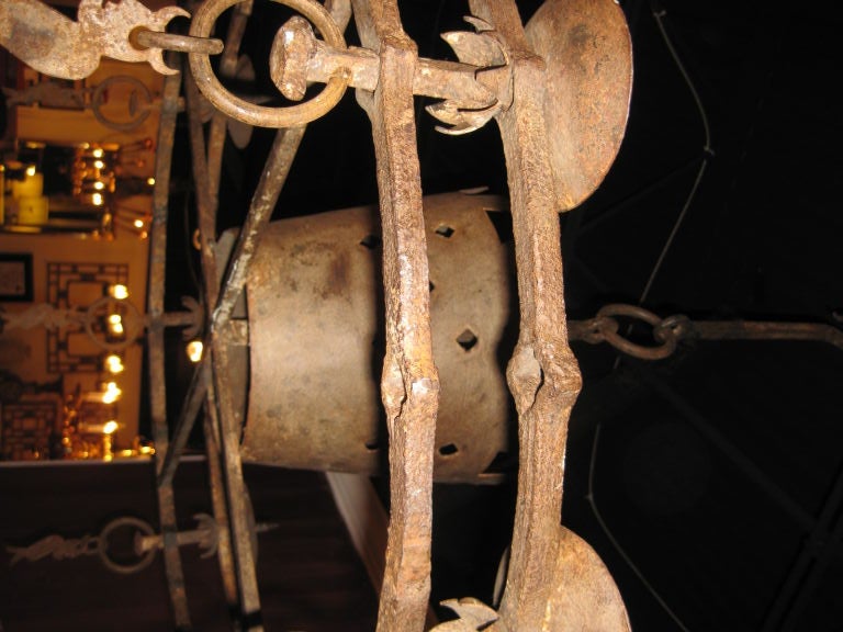 Iron chandelier with protecting demons hanging below each of the nine candleholders.