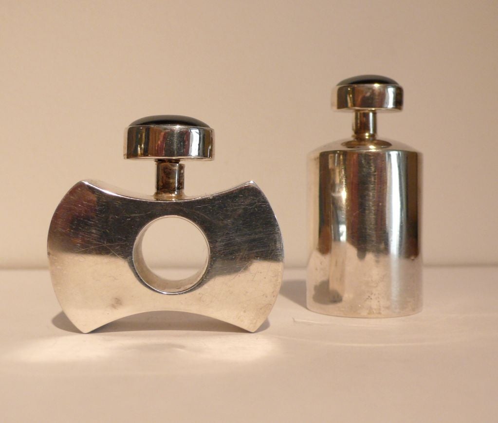 Small, hand crafted .925 silver perfume bottles made in Taxco, c. 1985 in an interesting and vaguely machine age style. Stoppers topped with semi-precious stone, probably lapiz.  Low bottle measures H1.5
