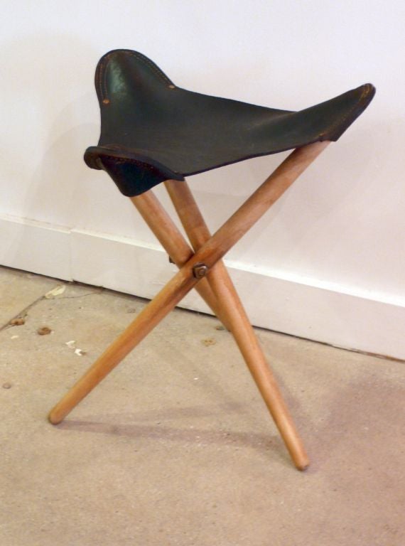 Small tripod folding stool, modeled on an artist's stool, with birch tapered dowel legs and Argentine leather sling.  Produced in Denmark, c. 1950's.  Leather sling has a green tint--remains of the original color--hand-tooled edges, and bears a