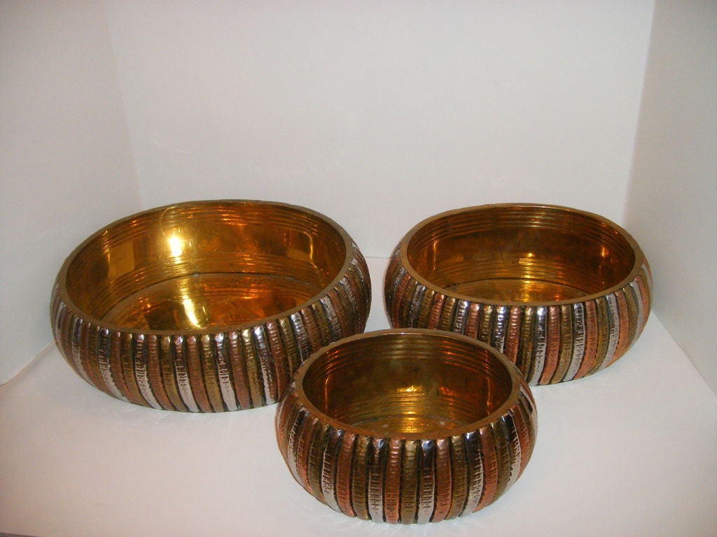 A set of 3 metal canisters made of copper, brass and tin. <br />
The larger one measures 16