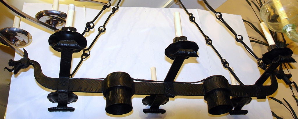 CIRCA 1900 Spanischer schmiedeeiserner Kronleuchter mit gehämmerten Drachenköpfen, sechs Oberlichtern und zwei Unterlichtern in der Mitte des Körpers.

Abmessungen:
Höhe: 39