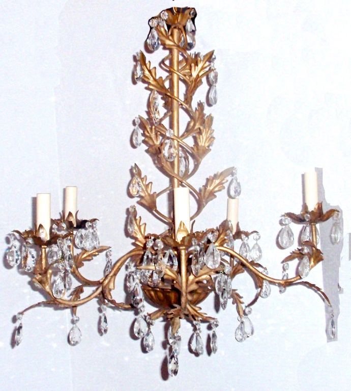 Lustre italien en métal doré avec pendentifs en cristal, vers les années 1940. Le corps est en motif de vigne torsadée avec un motif de feuillage.
Mesures :
Diamètre : 23.5